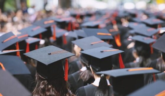 Students stand at a graduation ceremony.