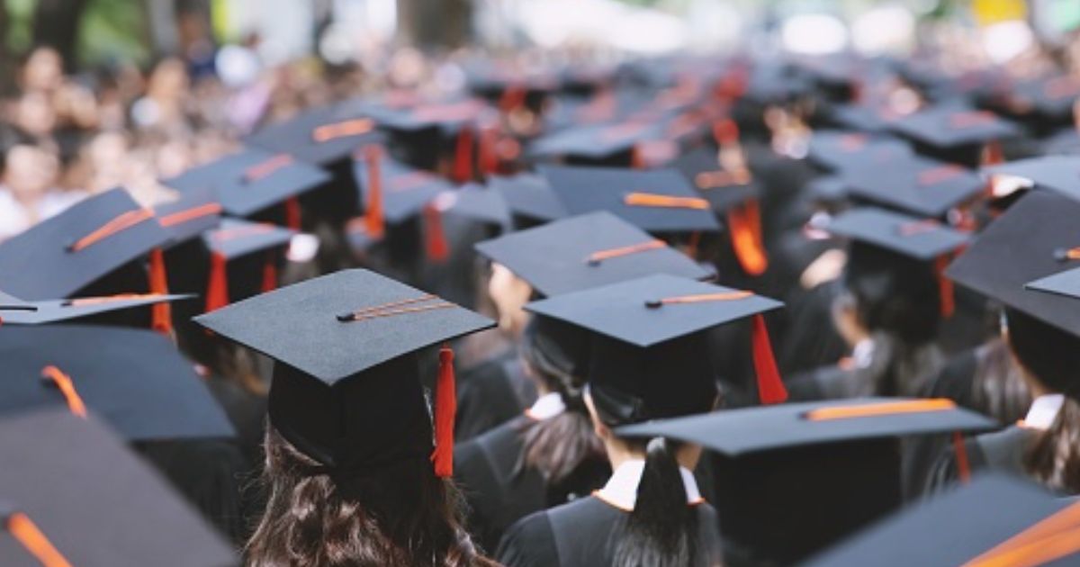 Students stand at a graduation ceremony.