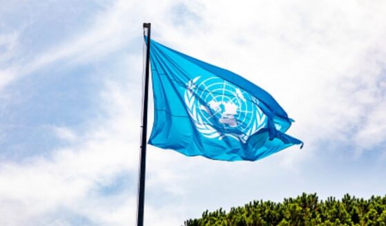 The United Nations flag waves in the sky.