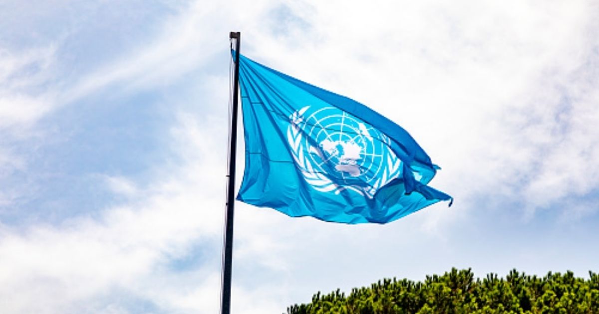 The United Nations flag waves in the sky.