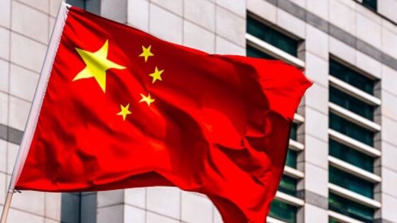 A Chinese flag flies near a large building.