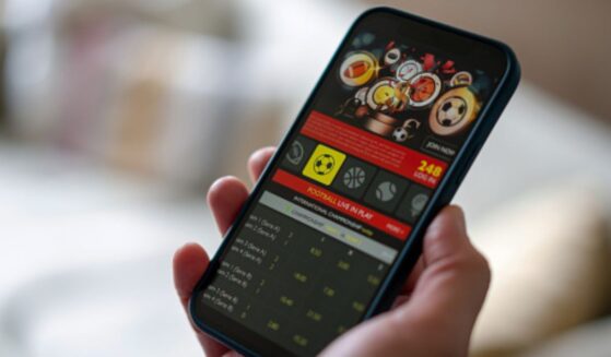 A phone screen is displayed with a gambling app on the interface.