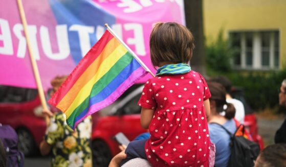 A child sits on her mother's shoulders at an LGBT pride event.