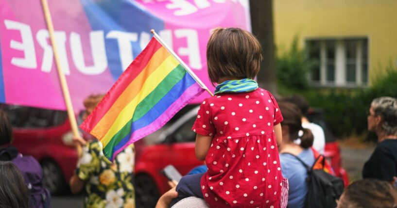 A child sits on her mother's shoulders at an LGBT pride event.