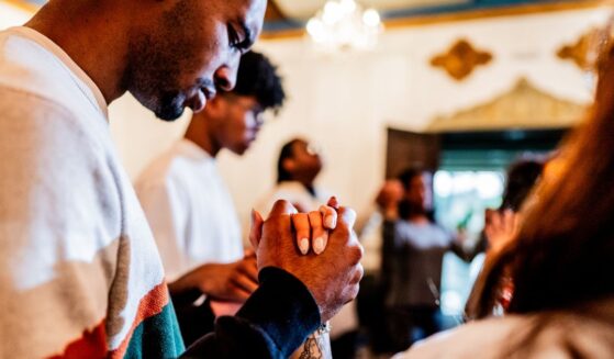 A young man prays with others during a church service.