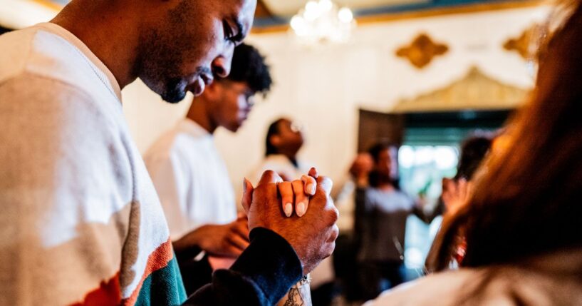 A young man prays with others during a church service.