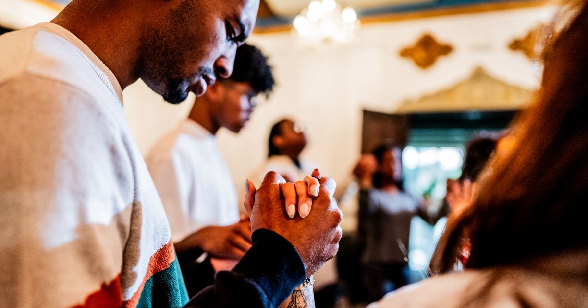 A young man prays with others during a church service.