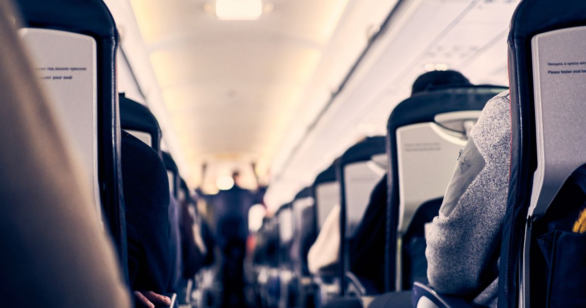 The interior of a plane as passengers sit in their seats.