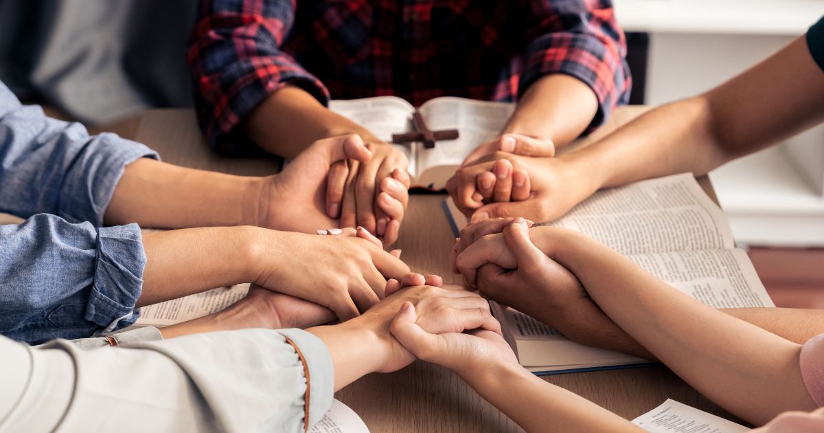 An image of young Christians holding hands and praying.