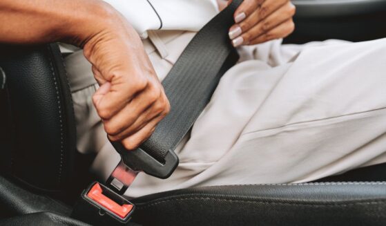 A close-up of someone putting on a seat belt.