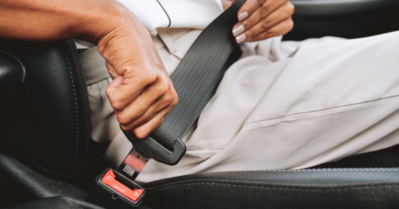 A close-up of someone putting on a seat belt.
