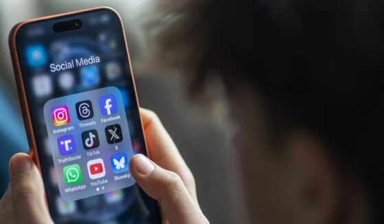 A young boy holds an iPhone and views various apps.