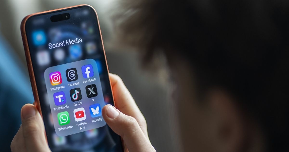 A young boy holds an iPhone and views various apps.