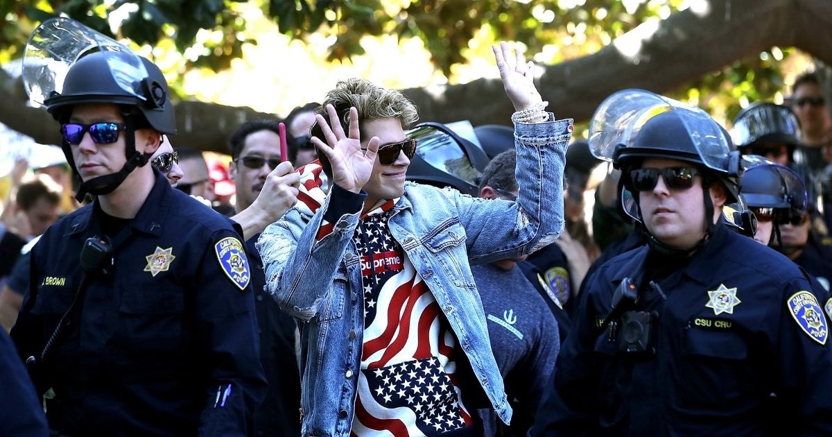 Right-wing commentator Milo Yiannopoulos is escorted by police officers after appearing at a free-speech rally at U.C. Berkeley on Sept. 24, 2017, in Berkeley, California.