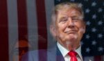 An American flag is reflected off bulletproof glass as President Donald Trump watches the end of the NTT Indycar Series Sunday in Washington, D.C.