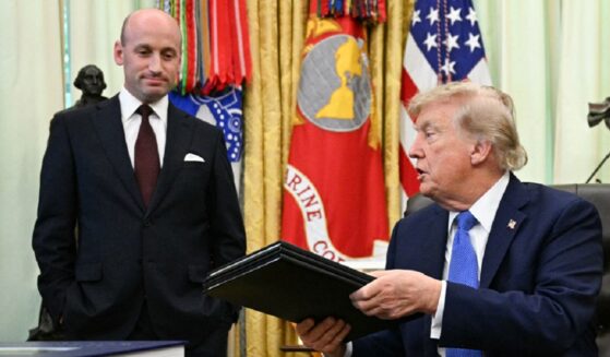 President Donald Trump holds binders containing two executive orders he signed Thursday targeting birthright citizenship for some individuals and "birth tourism." With him is White House Deputy Chief of Staff Stephen Miller.