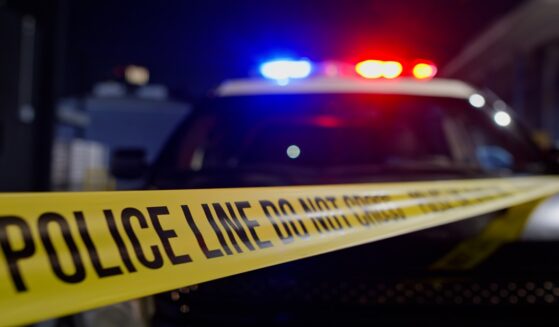 Police lights flash above crime scene tape in a stock photo.