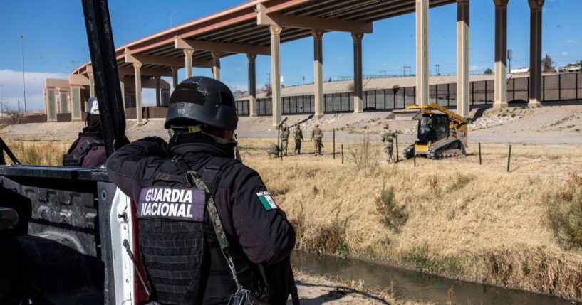 A Mexican National Guard soldier stands on the south side of the border as Texas National Guard troops place posts to extend a secondary fence at the U.S.-Mexico border on Jan. 7, 2023, as viewed from Ciudad Juarez, Mexico.