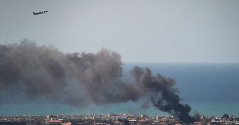 A MEA commercial airplane is flying above the smoke after an IDF airstrike on March 17, 2026, in Beirut, Lebanon.