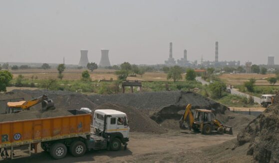An excavator loads coal sand into a transport truck near a thermal power plant in a coal yard, in an industrial area on April 21, 2026, in the outskirts of New Delhi, India.