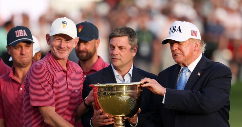 Captain Brandt Snedeker of the U.S. team lifts the trophy after their 17-13 win during the trophy ceremony as President Donald Trump looks on following the Sunday's Singles on day four of the Presidents Cup 2026 at Medinah Country Club on Sept. 27, 2026, in Medinah, Illinois.