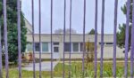 An empty school building behind a purple metal gate on a cloudy autumn day.
