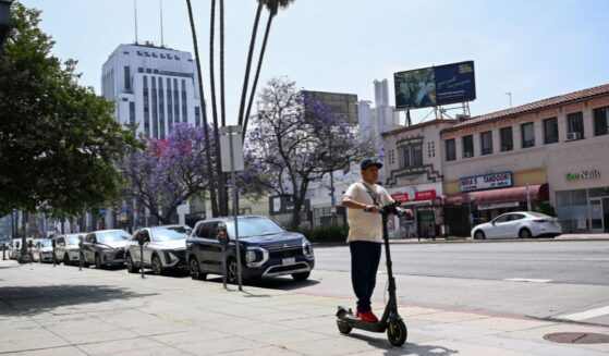 A pedestrian rides an electric scooter along Wilshire Boulevard in the Mid-Wilshire neighborhood on June 11, 2025, in Los Angeles, California.