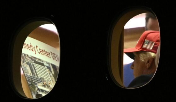 President Donald Trump is seen aboard Air Force One Wednesday, checking a large printout that appears to depict demolition of the Kennedy Center.