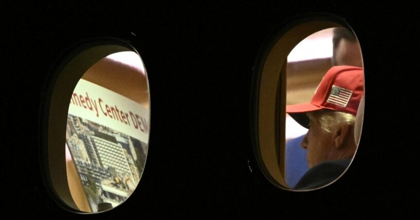 President Donald Trump is seen aboard Air Force One Wednesday, checking a large printout that appears to depict demolition of the Kennedy Center.