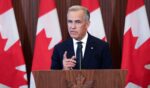 Canadian Prime Minister Mark Carney speaks to the press behind a wooden podium as Canadian flags stand behind him near a wall on September 8, 2026.