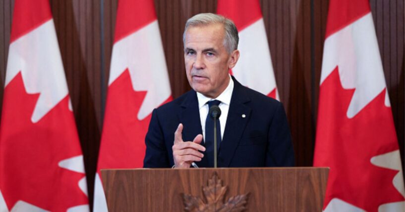Canadian Prime Minister Mark Carney speaks to the press behind a wooden podium as Canadian flags stand behind him near a wall on September 8, 2026.