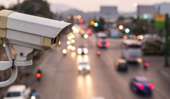 A traffic surveillance camera is pictured above a street at dusk.