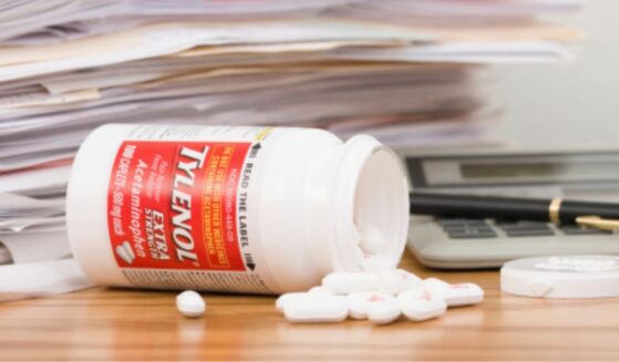 A Tylenol bottle is flipped over with pills pouring out.