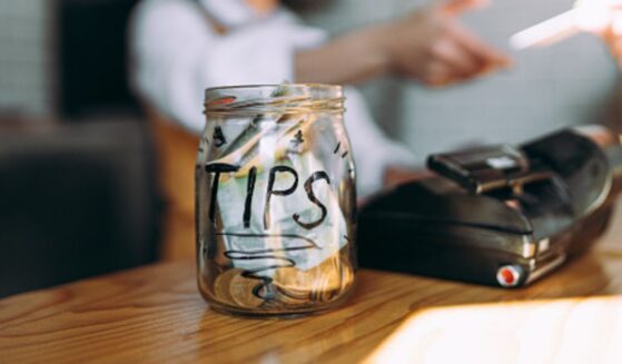 A tip jar sits full on a cashier counter.
