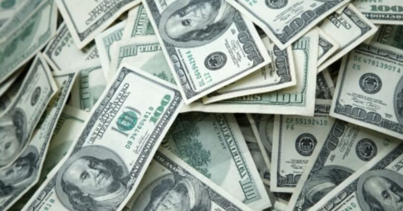 Hundred dollar bills lay across a table.