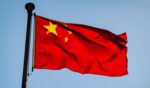 The Chinese flag flies in the blue sky.