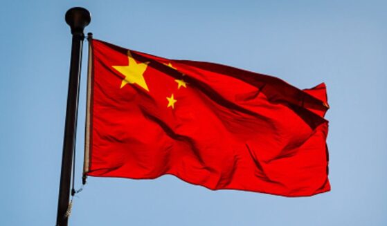 The Chinese flag flies in the blue sky.