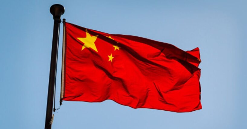 The Chinese flag flies in the blue sky.