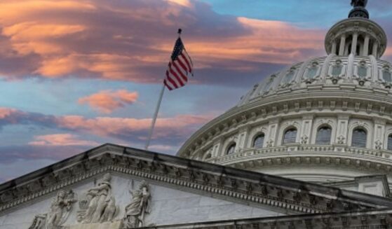 The Capitol Building stands while the American flag flies at dusk.