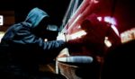 A thief tries to pry open a car door.