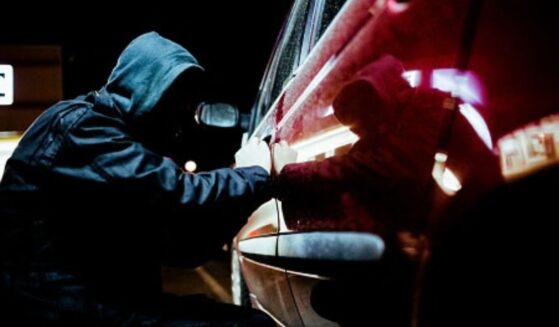A thief tries to pry open a car door.