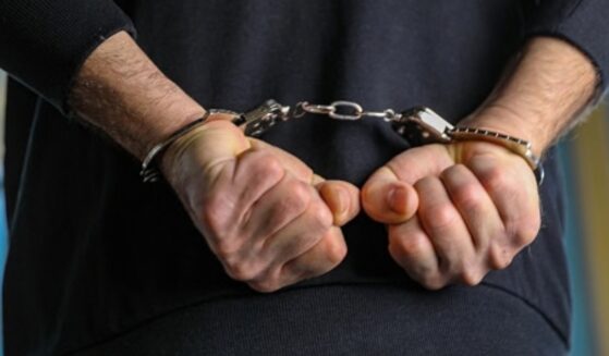 A man is pictured handcuffed in a dark blue shirt.