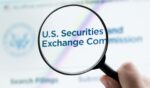 The Securities and Exchange Commission logo is viewed on a website through a magnifying glass.
