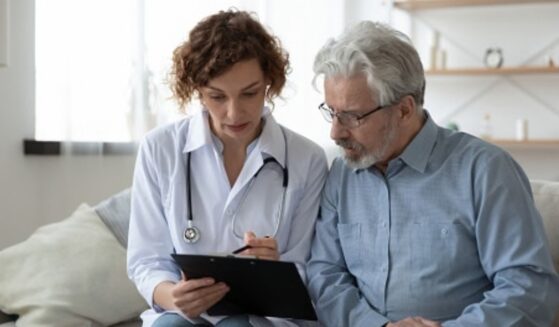 A doctor going over information on a clipboard with their patient.