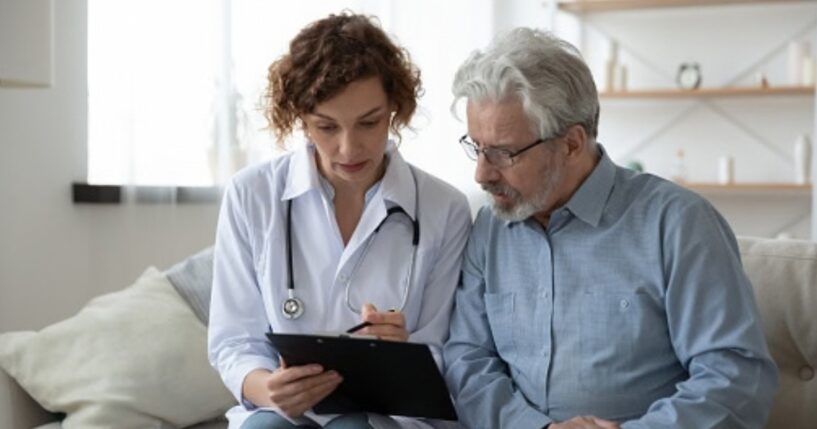 A doctor going over information on a clipboard with their patient.
