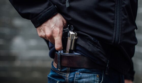 A man pulls a gun from his jeans pocket.