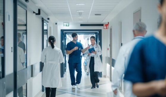 A hospital hallway is pictured as people walk through it.