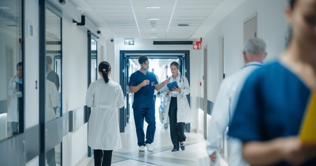 A hospital hallway is pictured as people walk through it.