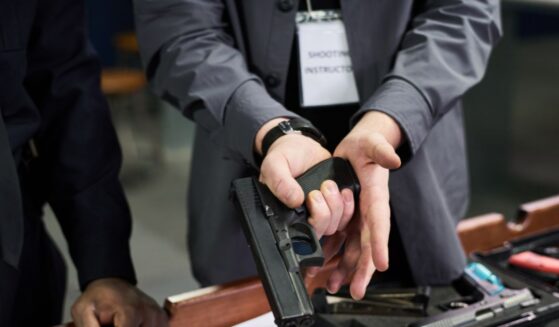 A close-up shot of an instructor demonstrating proper firearm safety.