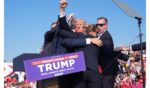 Former president Donald Trump, surrounded by Secret Service officers, raises his arm with blood on his face after an assassination attempt during a campaign rally July 13, 2024, in Butler, Pennsylvania.
